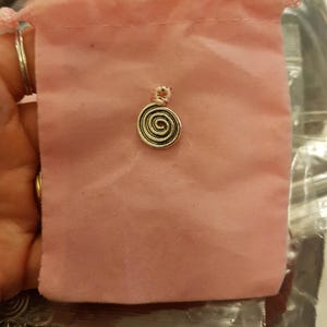 May include: A pink velvet pouch with a silver spiral charm. The pouch is labelled "Pendulum / Rune Bag".