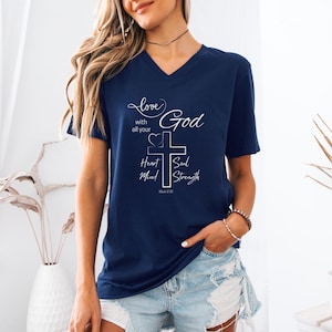 May include: Navy blue V-neck t-shirt with white script and a cross design. The text includes "love with all your God Heart Soul Mind Strength" and "Mark 12:30". The shirt is a casual wear item.