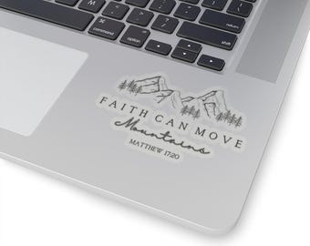Puede incluir: Una pegatina transparente con el texto "FAITH CAN MOVE Mountains" y "MATTHEW 17:20" en un estilo manuscrito. La pegatina presenta una ilustración en blanco y negro de montañas y árboles. La pegatina está colocada en un portátil plateado.