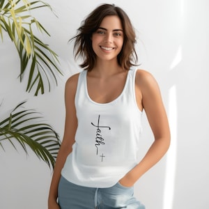 Könnte beinhalten: Weißes Tanktop mit dem Wort "Faith" in schwarzer Schrift, darunter ein Kreuz. Das Tanktop ist ärmellos und aus einem weichen Material gefertigt.