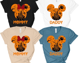 May include: Four short-sleeved t-shirts in black, white, tan, and blue. Each shirt features a Halloween-themed design with a Mickey Mouse head shape, a castle, bats, and the words "Mommy" or "Daddy" in orange.
