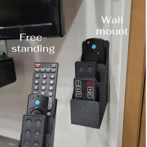 May include: Two black remote control organizers, one free-standing and one wall-mounted, each holding multiple remotes. The free-standing organizer is on a surface, while the wall-mounted one is attached to a wall. The image includes the text "Free-standing" and "Wall mount".