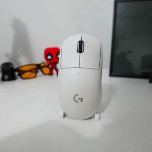 May include: A white wireless gaming mouse with a black G logo on the top. The mouse has a black scroll wheel and two black buttons on the top.