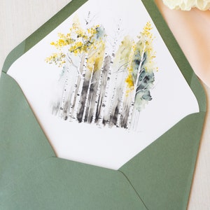 May include: A watercolor painting of a forest scene with birch trees and yellow leaves. The painting is on a white card and is inside a green envelope.