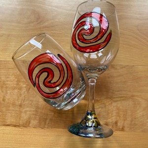 Puede incluir: Dos copas de vino con un dise&ntilde;o de espiral rojo y negro. La copa de la izquierda es un vaso y la copa de la derecha es una copa de vino con tallo.