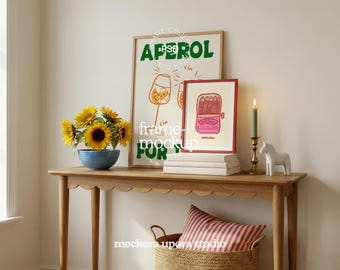 May include: A mock-up of a room setting with a wooden table, featuring framed art prints, sunflowers in a blue bowl, and a candle. One print says "APEROL" in green. The other print shows a sardine can. A white horse figurine is on the table.