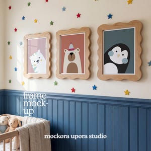 Può includere: Tre stampe artistiche incorniciate di animali, con un orso bianco, un orso marrone e un pinguino, esposte su una parete con decorazioni a stella. Le cornici hanno un bordo ondulato. La parete è dipinta di crema e blu, con una culla in primo piano.