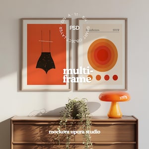 Puede incluir: Dos láminas enmarcadas con una estética moderna de mediados de siglo. Una presenta una forma abstracta negra sobre un fondo naranja. La otra tiene círculos concéntricos naranjas y la palabra "Bauhaus". Una lámpara con forma de hongo se encuentra sobre un mueble de madera.