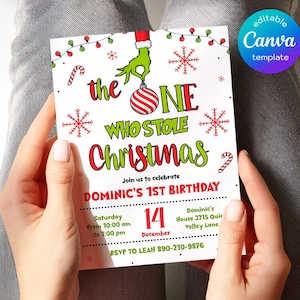 May include: A white rectangular birthday invitation card featuring a green hand holding a red and white striped ornament. The text reads: the ONE WHO STOLE Christmas, Join us to celebrate DOMINIC'S 1ST BIRTHDAY, Saturday 14 December, and RSVP details.