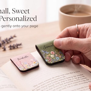May include: Two magnetic page clips featuring floral patterns and personalised names. One clip is pink with the name Isabella, and the other is green with the name Samuel and a dragonfly illustration. Both clips are shown resting on an open book page.