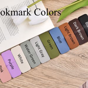 May include: A collection of rectangular magnetic bookmarks arranged in a diagonal row, labelled with colours including pink, purple, white, water green, light grey, green, blue, light brown, dark brown, and black, with the text Bookmark Colours.