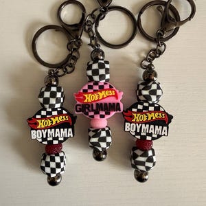 May include: Three keychains with black and white checkered beads, red accents, and the text "Hot Mess Boymama" or "Girlmama" in red and white. Each keychain has a metal clasp and chain.