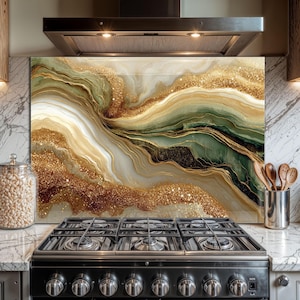 May include: A decorative kitchen backsplash with an abstract design. The artwork features flowing patterns in shades of gold, green, and white, with sparkling glitter accents. The backsplash is installed behind a black gas stove.