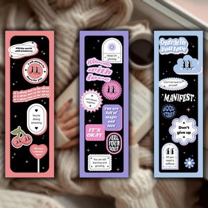 May include: Three colorful bookmarks with inspirational quotes and retro-style illustrations. The bookmarks feature phrases like "Fill the world with kindness," "Bloom with love," and "Create the life you love." Each bookmark has a different color scheme, including pink, purple, and blue.
