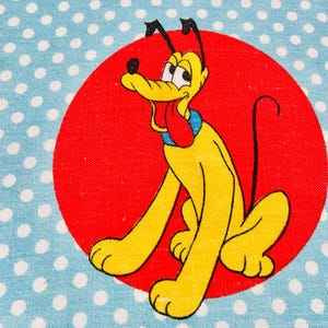 Könnte beinhalten: Ein gelber Zeichentrickhund mit roter Zunge und schwarzen Ohren sitzt vor einem roten Kreis. Der Hintergrund ist hellblau mit weißen Punkten. Der Hund hat ein blaues Halsband.