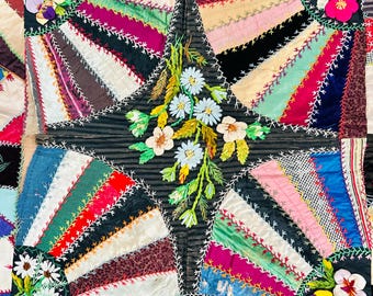 May include: A colorful, handmade quilt with a starburst design. The quilt features various fabrics in shades of red, pink, green, and brown, with white stitching. Embroidered flowers and floral accents are placed throughout the quilt, adding a decorative touch.