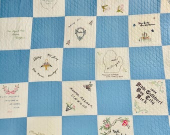 Puede incluir: Un edredón vintage con un patrón de cuadros azules y blancos. Cada cuadrado blanco presenta diseños florales bordados y nombres y lugares escritos a mano. El edredón es un artículo hecho a mano, que muestra un diseño de patchwork.