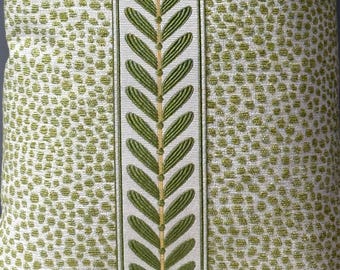 May include: A square throw pillow featuring a textured off-white fabric with a repeating pattern of small, raised lime green dots. A vertical central band displays an embroidered green leaf or fern motif on a cream-colored fabric background.