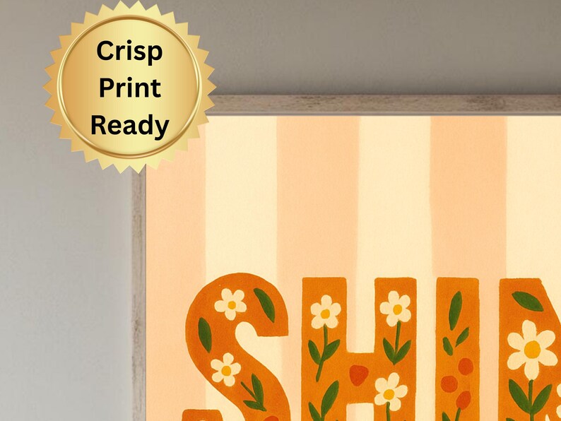 May include: A framed art print with the word "SHINE" in orange, floral-decorated letters. The background features vertical stripes in light orange and white. A gold seal with the text "Crisp Print Ready" is in the upper left corner.