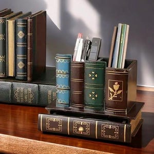 Op de afbeelding: Een decoratieve bureau-organizer ontworpen om op een stapel antieke boeken te lijken. De organizer heeft vakken voor pennen, potloden en andere kantoorbenodigdheden. Het kleurenschema omvat tinten bruin, groen en goud, met de tekst "SAMPLE TEXT" zichtbaar.