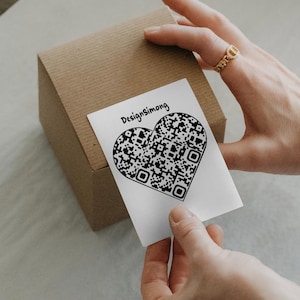 May include: A white card with the text "DesignSimong" and a black and white heart-shaped QR code.