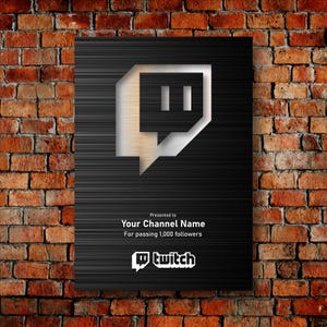 May include: A black plaque with a silver Twitch logo and the text "Presented to Your Channel Name For passing 1,000 followers." The plaque is mounted on a red brick wall.