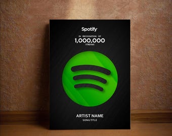 May include: A black Spotify poster with the Spotify logo in green and black. The poster reads "Spotify IN RECOGNITION OF 1,000,000 STREAMS" and has space for the artist name and song title. The poster is displayed on a wooden surface.