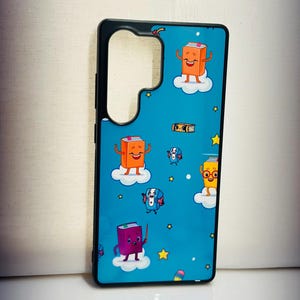 May include: A black phone case with a blue background and a pattern of cartoon books with faces. The books are on clouds and there are stars on the background.