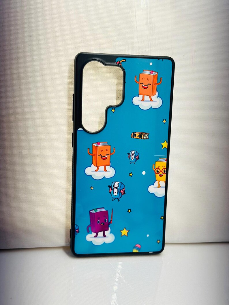 May include: A black phone case with a blue background and a pattern of cartoon books with faces. The books are on clouds and there are stars on the background.