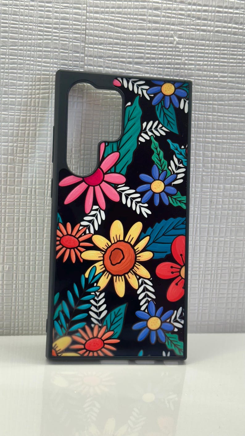 May include: Black phone case with a colorful floral design. The flowers are yellow, red, pink, blue, and orange. The leaves are green and white.
