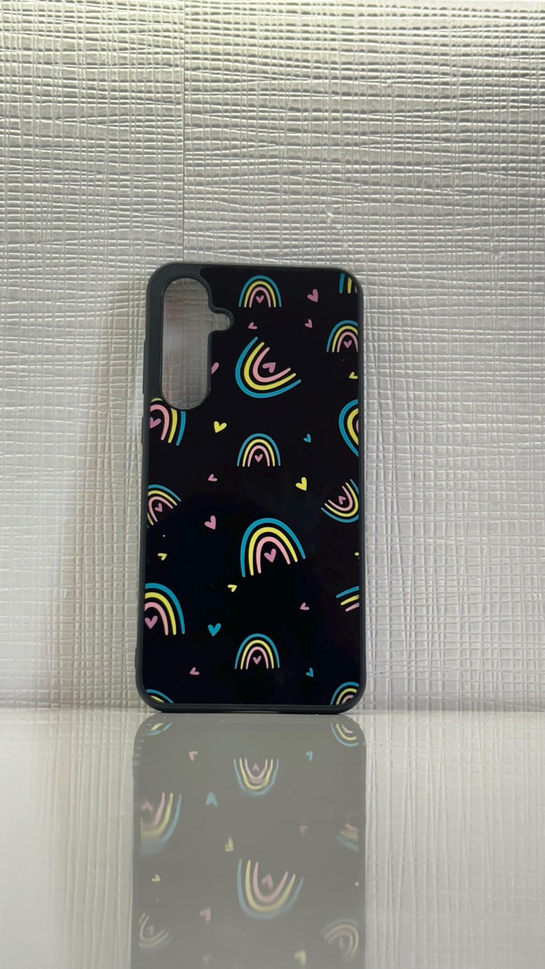 May include: Black phone case with a pattern of colorful rainbows and pink hearts.