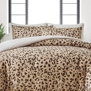 May include: A bed set featuring a duvet cover and pillow shams with a leopard print pattern in shades of brown and tan. The duvet cover has a solid white underside. The pillow shams have a white border.