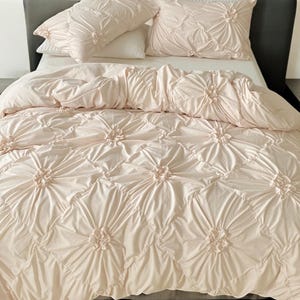 Op de afbeelding: Een roze dekbedovertrekset met een gestikt ontwerp met een bloemenpatroon. Het dekbedovertrek is gemaakt van zacht, comfortabel materiaal en is perfect om elke slaapkamer een vleugje elegantie te geven.