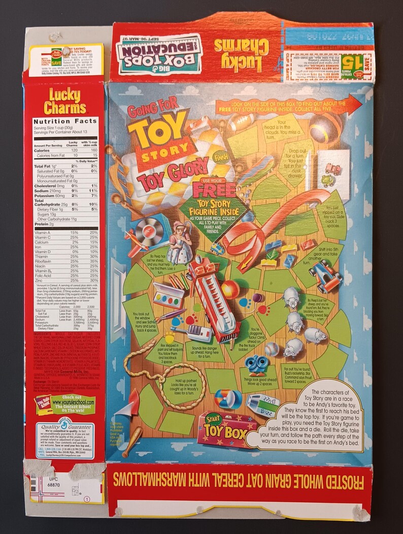 K&ouml;nnte beinhalten: Eine flachgedr&uuml;ckte Lucky Charms M&uuml;slipackung mit einer Toy Story Brettspielgrafik auf der R&uuml;ckseite. Das Design umfasst ein rotes, gelbes und blaues Farbschema mit Illustrationen von Spielzeug, einem Pfad und Textanweisungen f&uuml;r ein Wettrennen.