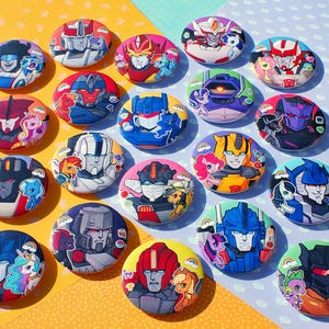 Pode incluir: Uma coleção de vinte botões redondos com ilustrações coloridas de vários personagens robôs combinados com pequenas figuras de pôneis. Cada botão exibe uma combinação única de personagens com cores vibrantes, incluindo detalhes em vermelho, azul, amarelo e roxo.