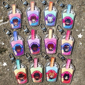 May include: Acrylic keyrings featuring bubble tea designs with anime-style characters. Each keyring is 7.6 cm and includes a silver clasp. The bubble tea cups have various colours and character designs.