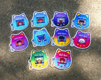 May include: A collection of colorful stickers featuring a cat-shaped digital pet design. Each sticker displays a character on a screen with the text "Pixel Icons". The stickers have a white border and are arranged on a textured surface.