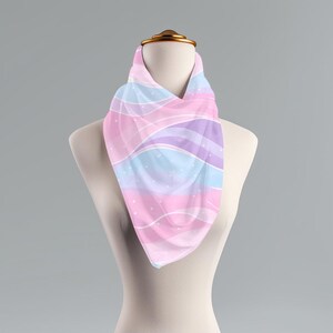 May include: A pink, blue, and purple patterned scarf with white polka dots. The scarf is draped over a white mannequin.