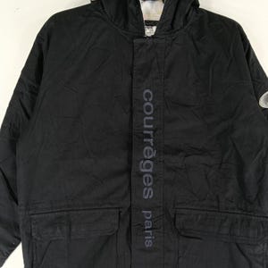 May include: Black hooded jacket with the text "courr&egrave;ges paris" vertically down the front. The jacket has a front zipper, two front pockets, and a small logo on the upper right sleeve. The jacket is made of a durable material.
