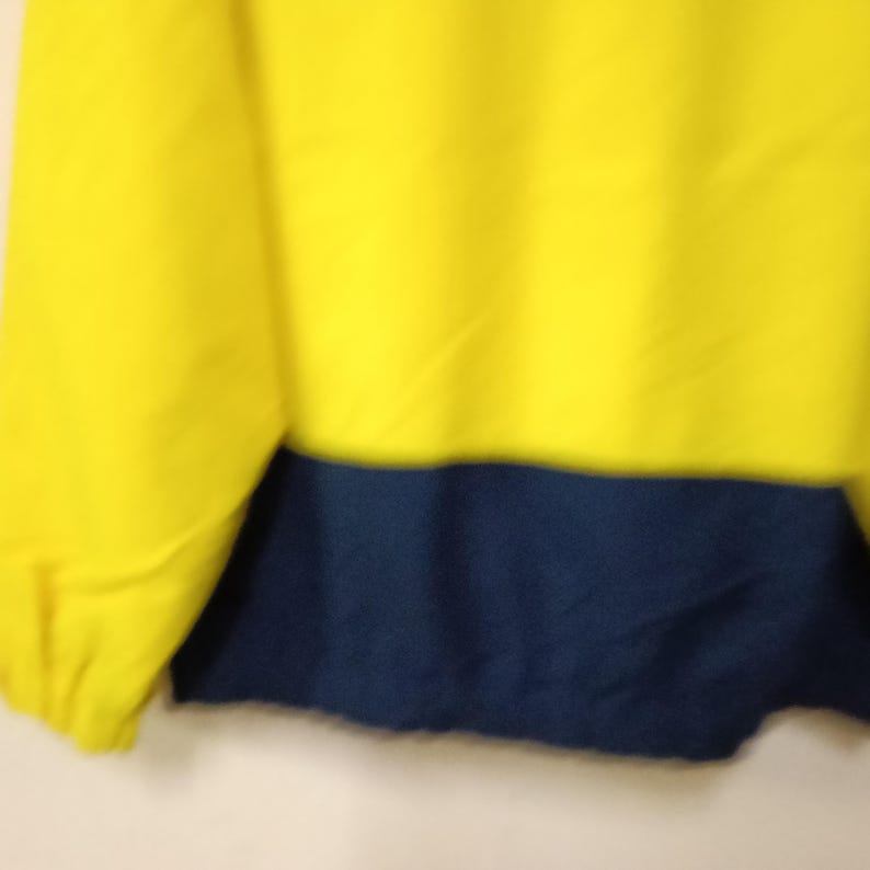 Puede incluir: Prenda amarilla y azul marino. La parte superior es de color amarillo brillante, mientras que la secci&oacute;n inferior es de color azul marino oscuro. La tela parece suave, posiblemente para ropa informal.