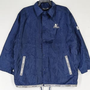 May include: A navy blue nylon jacket with a white zipper and white trim. The jacket has a logo on the left chest that says "Courtegans".