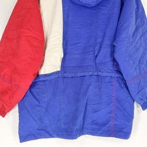 May include: A vintage color-blocked jacket in red, white, and blue. The jacket features a hood and a front zipper. The fabric has a crinkled texture. The jacket is a classic style.