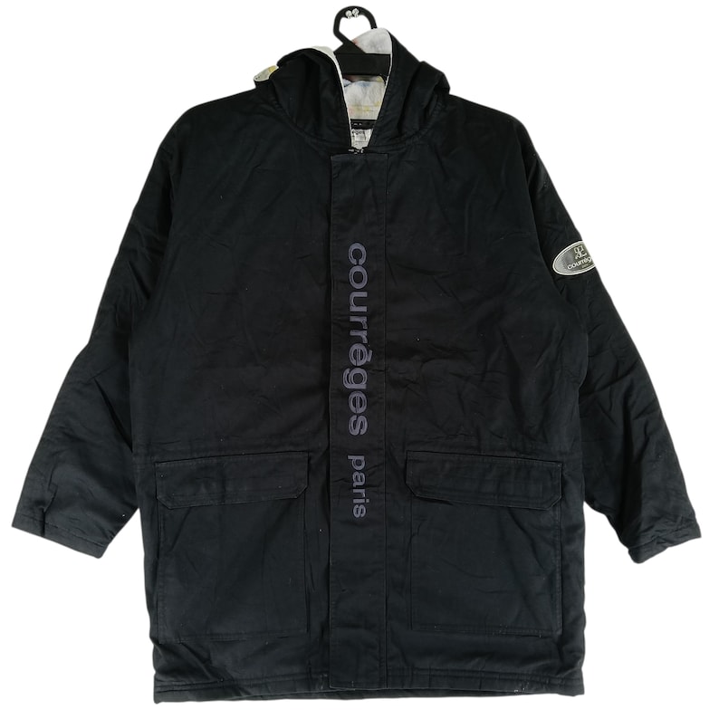 May include: Black hooded jacket with the text "courr&egrave;ges paris" vertically down the front. The jacket has two front pockets and a logo patch on the sleeve. The jacket is hanging on a black hanger.