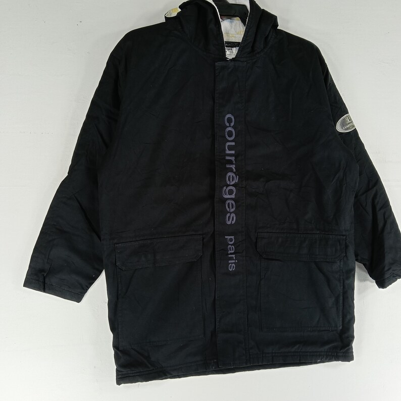 May include: Black hooded jacket with two front pockets and the text "courr&egrave;ges paris" vertically down the front. The jacket has a white and light-colored lining visible in the hood.