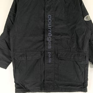 May include: Black Courr&egrave;ges Paris jacket with two front pockets and a vertical logo on the front. The jacket has a subtle sheen and a small logo patch on the upper right sleeve.