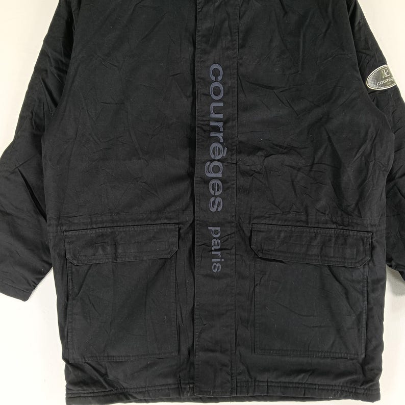 May include: Black Courr&egrave;ges Paris jacket with two front pockets and a vertical logo on the front. The jacket has a subtle sheen and a small logo patch on the upper right sleeve.