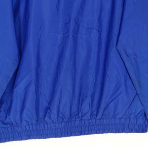 May include: A royal blue jacket with a gathered elastic waistband. The jacket is made of a lightweight, possibly nylon, material. The sleeves are visible on the left side of the image.