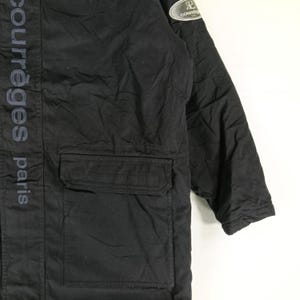May include: Black jacket with a pocket and the text "courr&egrave;ges paris" vertically down the side. A small patch with the brand logo is on the upper sleeve. The jacket appears to be made of a durable material.