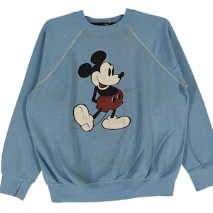 Puede incluir: Una sudadera de color azul claro con un gráfico vintage de Mickey Mouse en la parte delantera. El gráfico es de color negro, rojo y blanco.