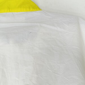 May include: Close-up of a white fabric with a yellow trim. The fabric appears to be thin and slightly translucent, with subtle textures and folds. The yellow trim is a bright, solid color.